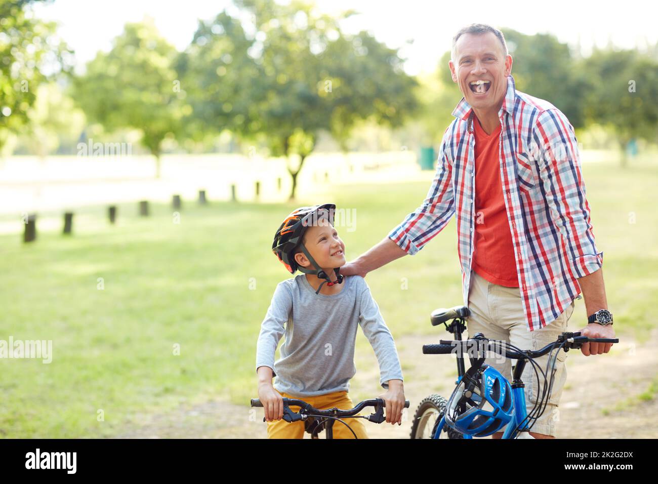 Hes a better rider than me now. Portrait of a father and son riding bicycles in a park. Stock Photo