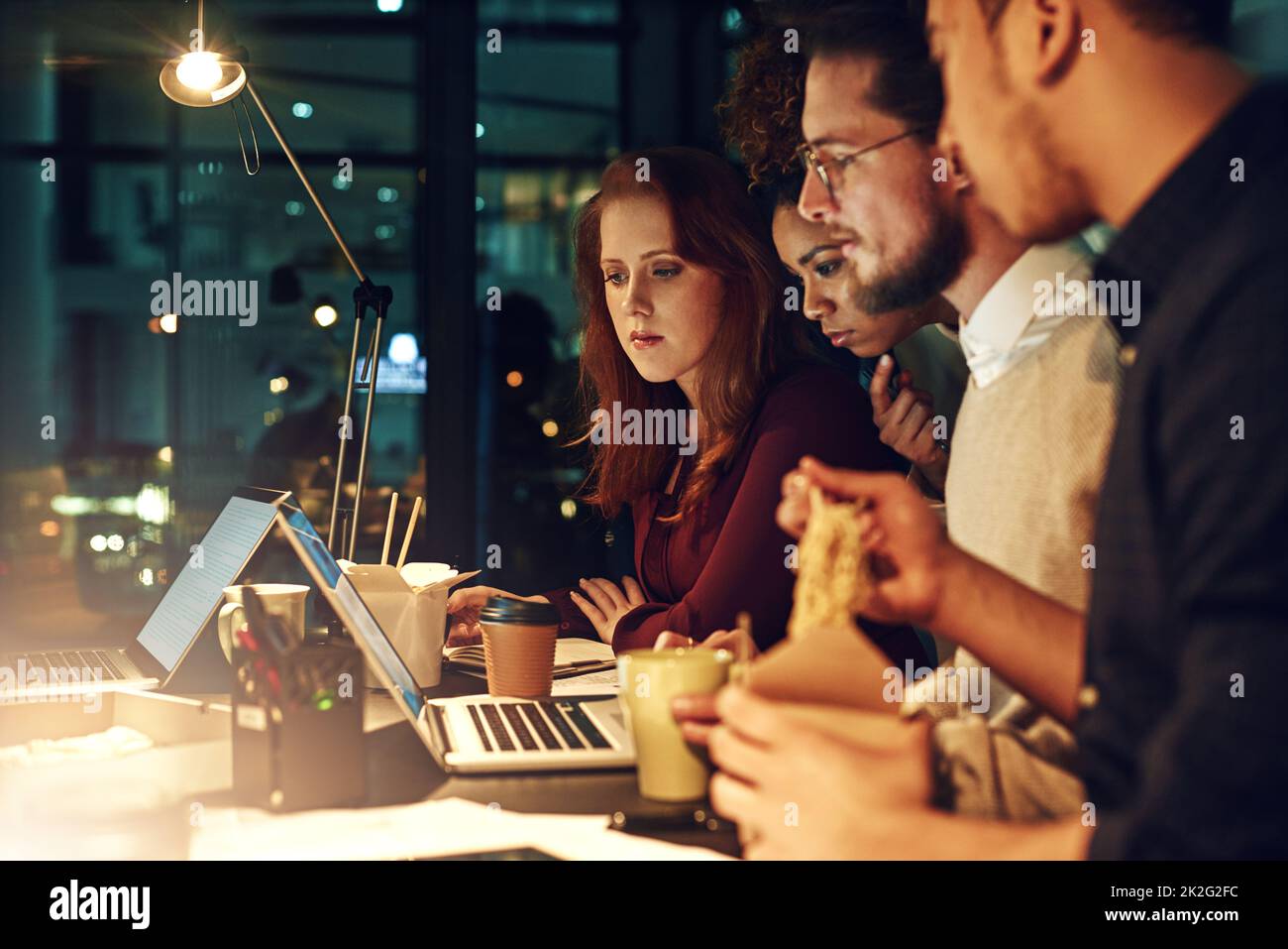 Deadlines wait for no one. Shot of a business team using a laptop together on a night shift at work. Stock Photo