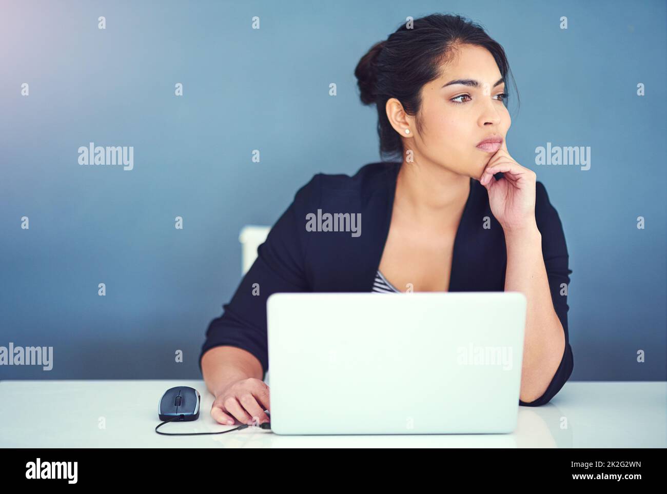 Just another day at the office. Cropped shot of a young businesswoman looking distracted at her desk. Stock Photo