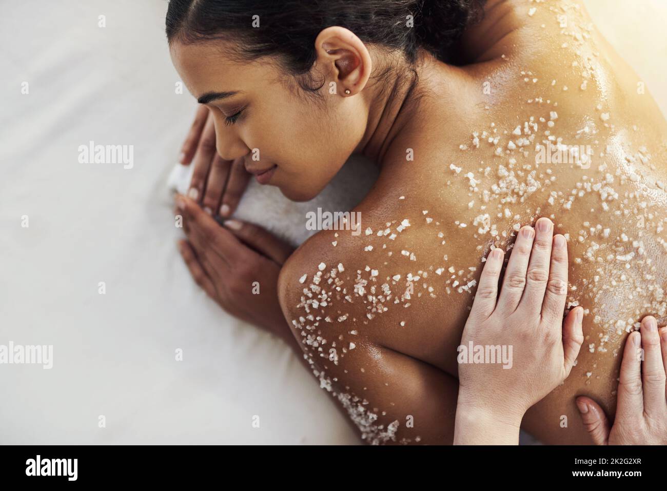 Scrubbing away dead skin to reveal a new you. Shot of a young woman getting an exfoliating massage at a spa. Stock Photo