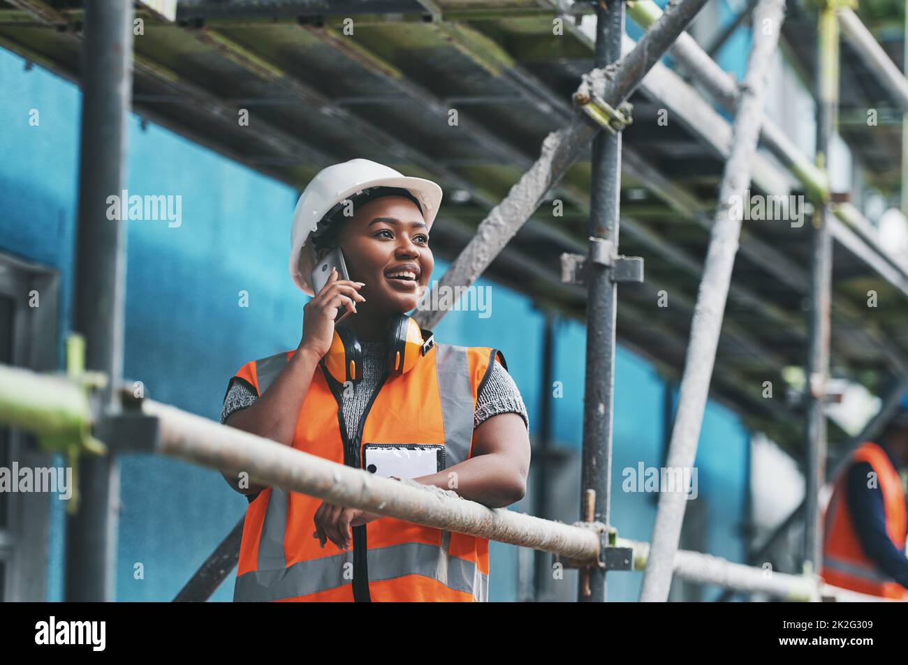 Monitoring the conception and execution of a new build. Shot of a young woman talking on a cellphone while working at a construction site. Stock Photo