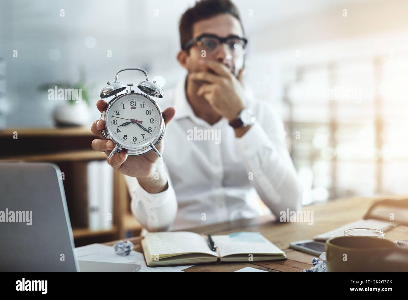 Dont let time spiral out of your control. Portrait of a young businessman looking stressed out while holding a clock in an office. Stock Photo