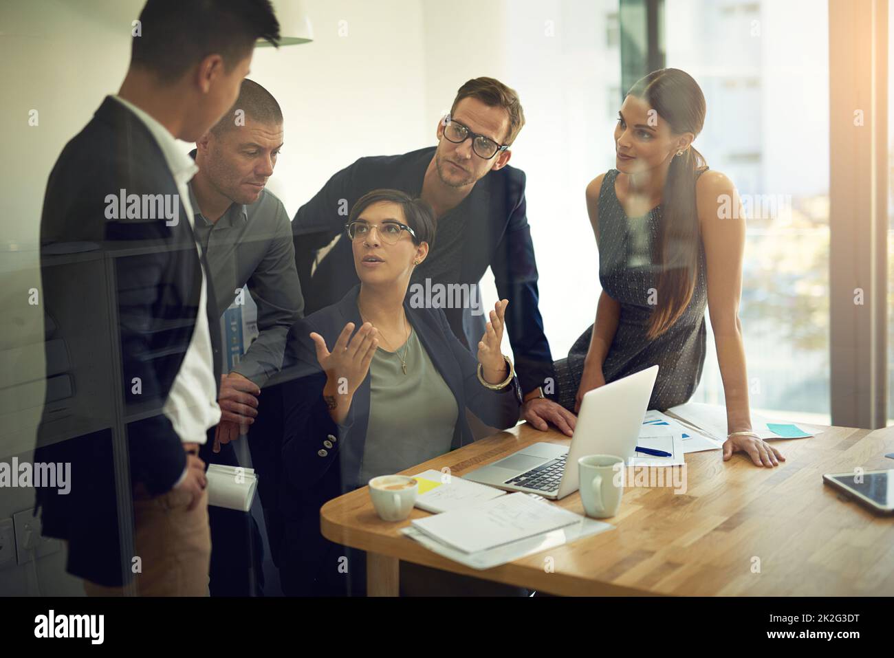 Collaboration challenges us to articulate what were great at. Shot of a group of coworkers discussing something on a laptop during a meeting. Stock Photo