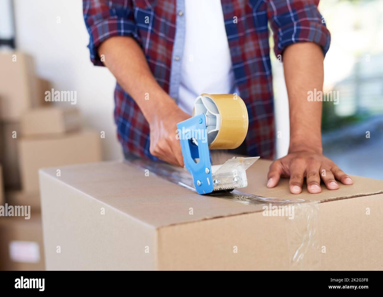 Safe and sealed. Shot of an unidentifiable man using a tape dispenser to close a box while