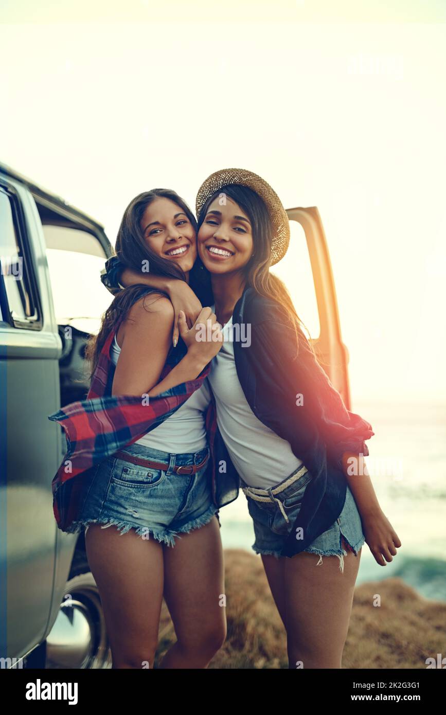 Everybody needs a road trip buddy and shes mine. Shot of two affectionate friends stopping at the beach during their roadtrip. Stock Photo