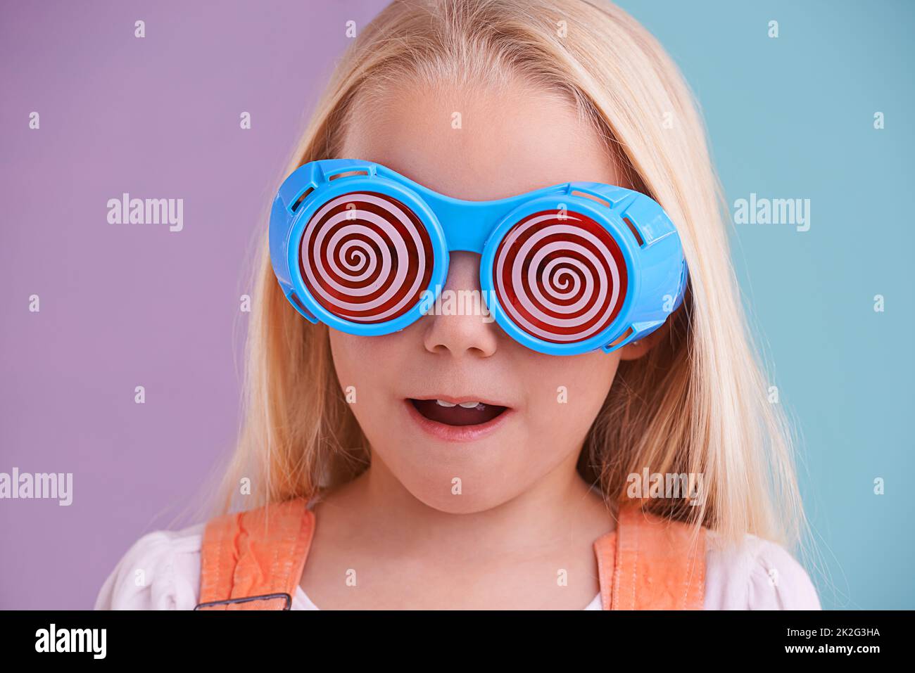 Going crazeeee. A cute little girl wearing funny sunglasses against a colorful background. Stock Photo