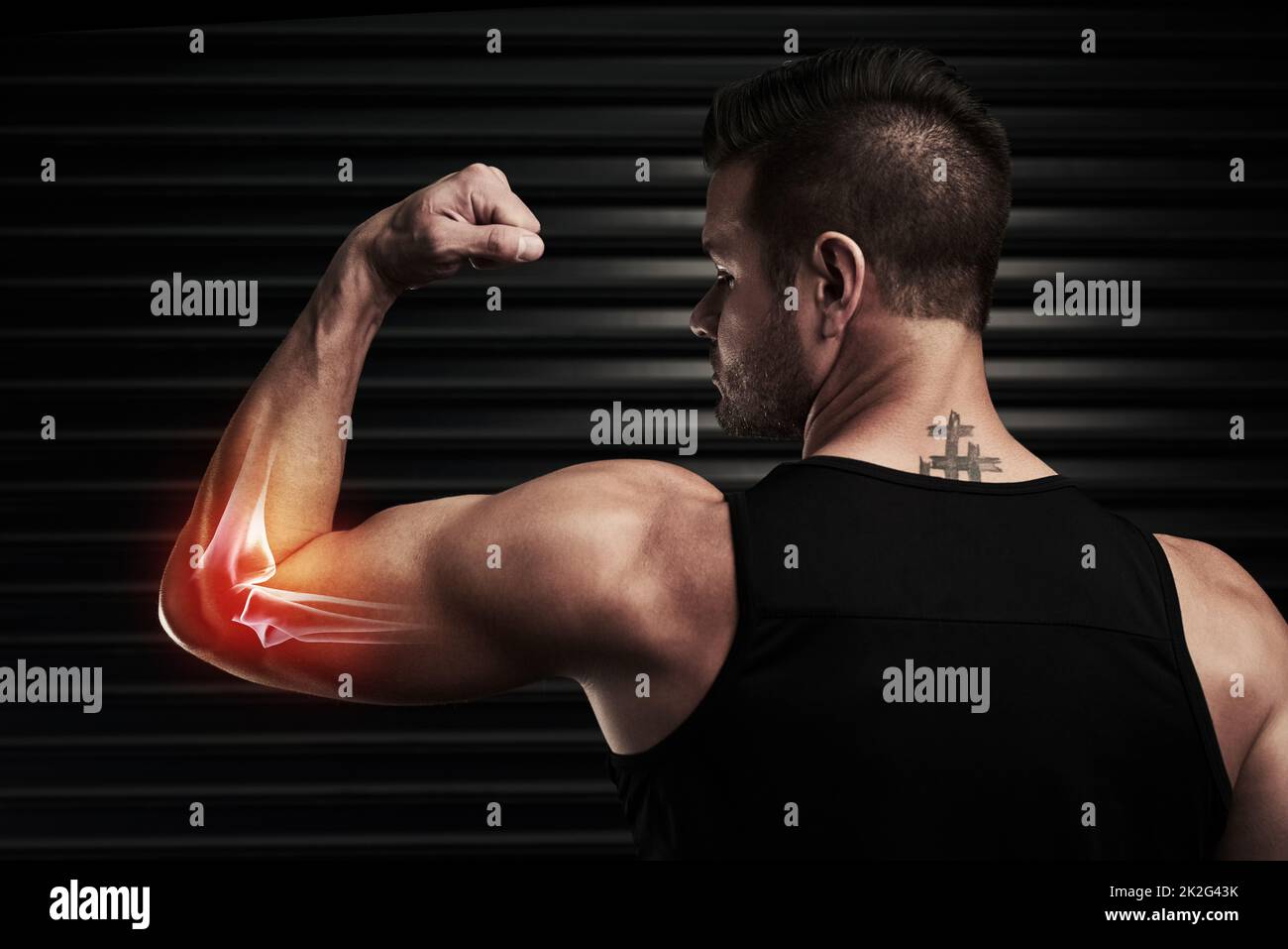 Pain is just a part of the package. Rearview shot of an athletic young man flexing with an elbow injury in the studio. Stock Photo