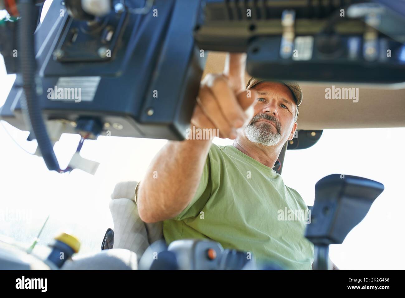The beginning of the farming day. Shot of a farmer working inside the cab of a modern tractor. Stock Photo