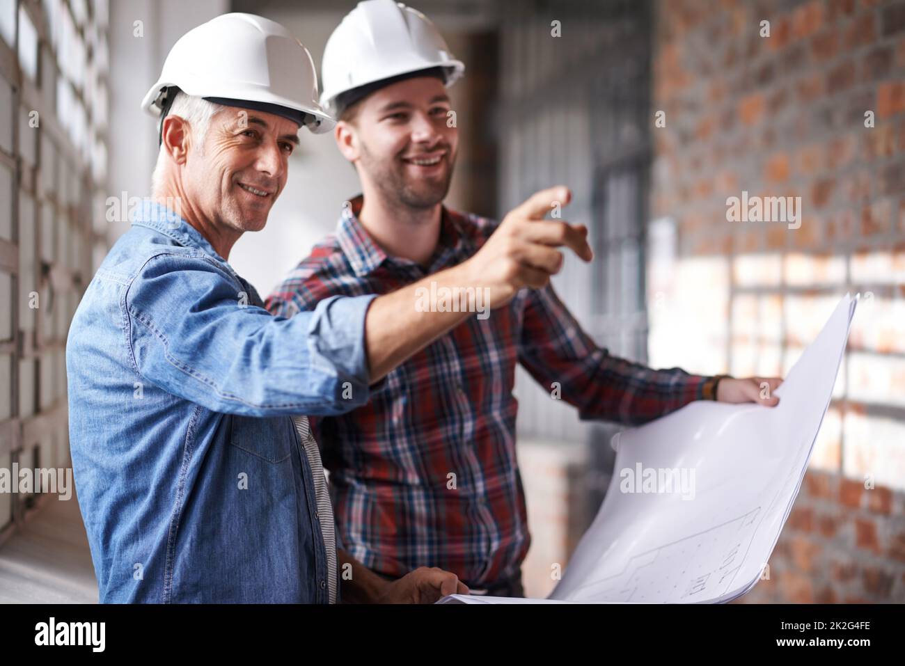 Lets start over there. Shot of two male architects wearing hardhats inspecting a building. Stock Photo