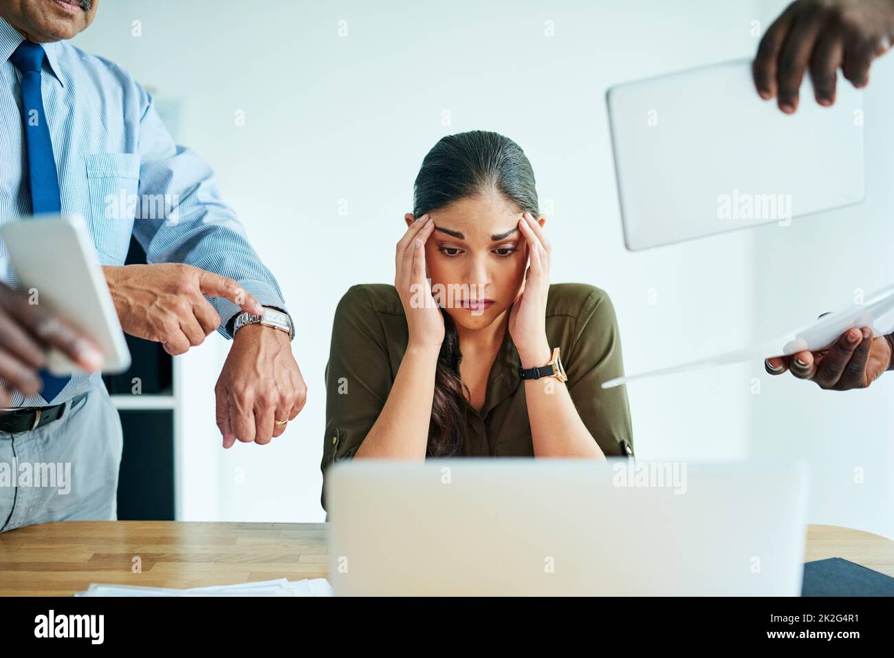 This is driving me insane. Shot of a stressed out businesswoman surrounded by colleagues needing help in an office. Stock Photo