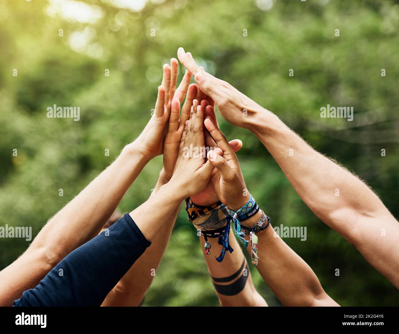 Time for some outdoor fun. Shot of a group of unrecognizable peoples hands raised in the air to form a huddle together outside during the day. Stock Photo