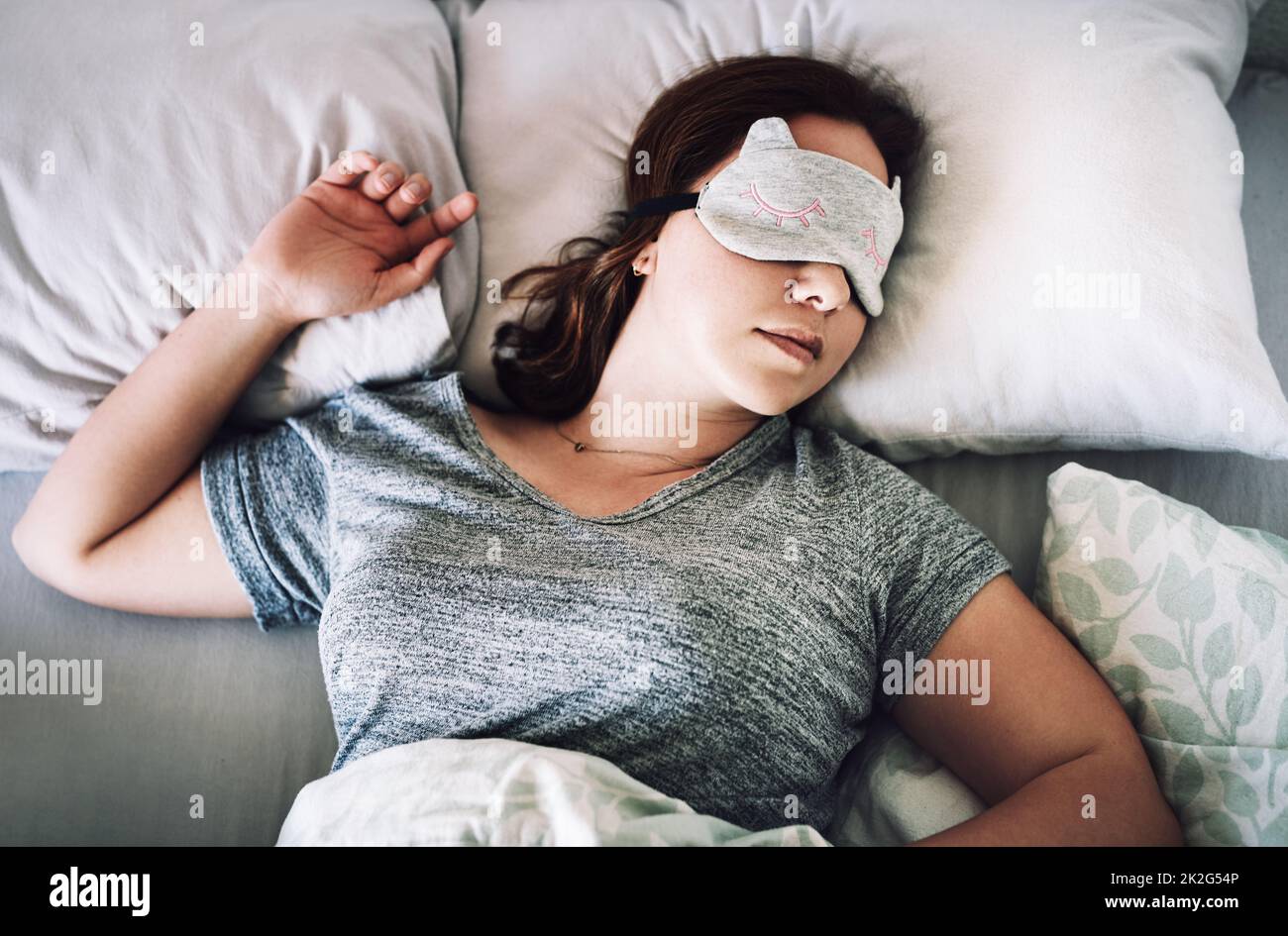 I deserve some peaceful sleep. High angle shot of an attractive young woman sleeping with a mask on her face in her bedroom at home. Stock Photo