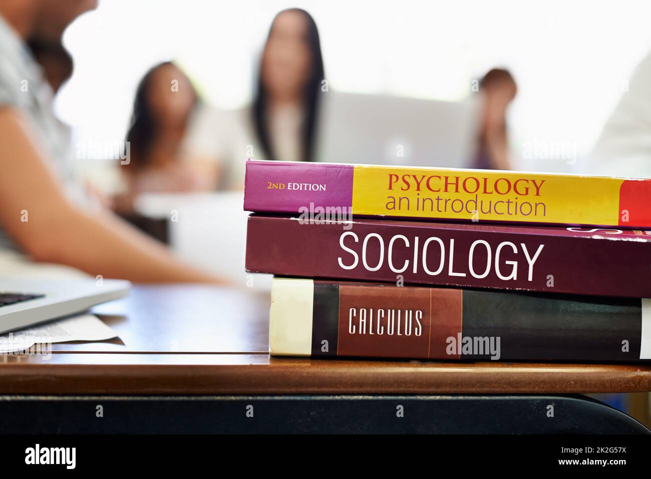 Social Studies. Cropped shot of university text books on a desk with students blurred in the background. Stock Photo