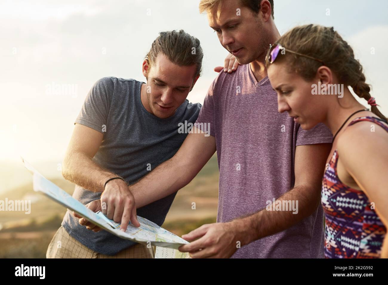 Where to wander next. Shot of three young hikers consulting a map while exploring a new trail. Stock Photo