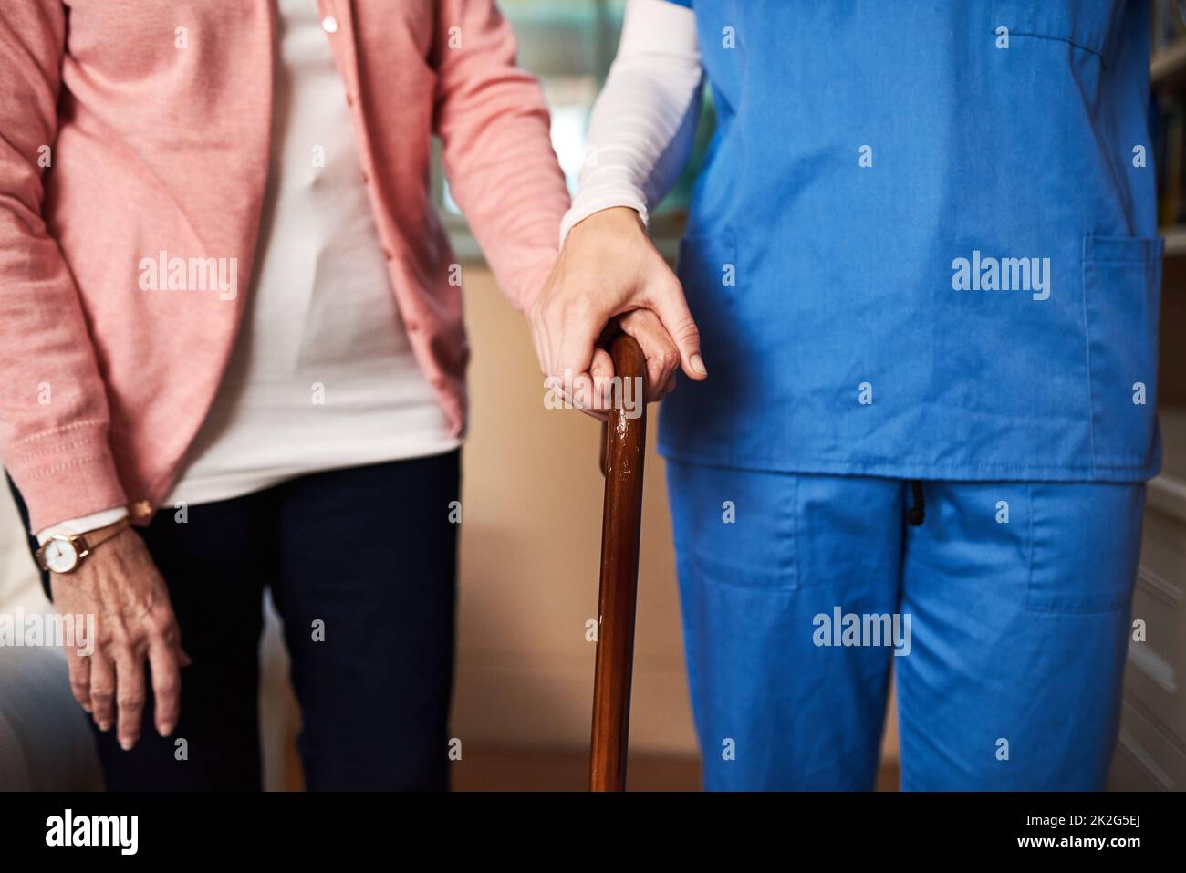 Ill be here every step of the way. Shot of a young nurse assisting a senior woman whos walking with a cane. Stock Photo