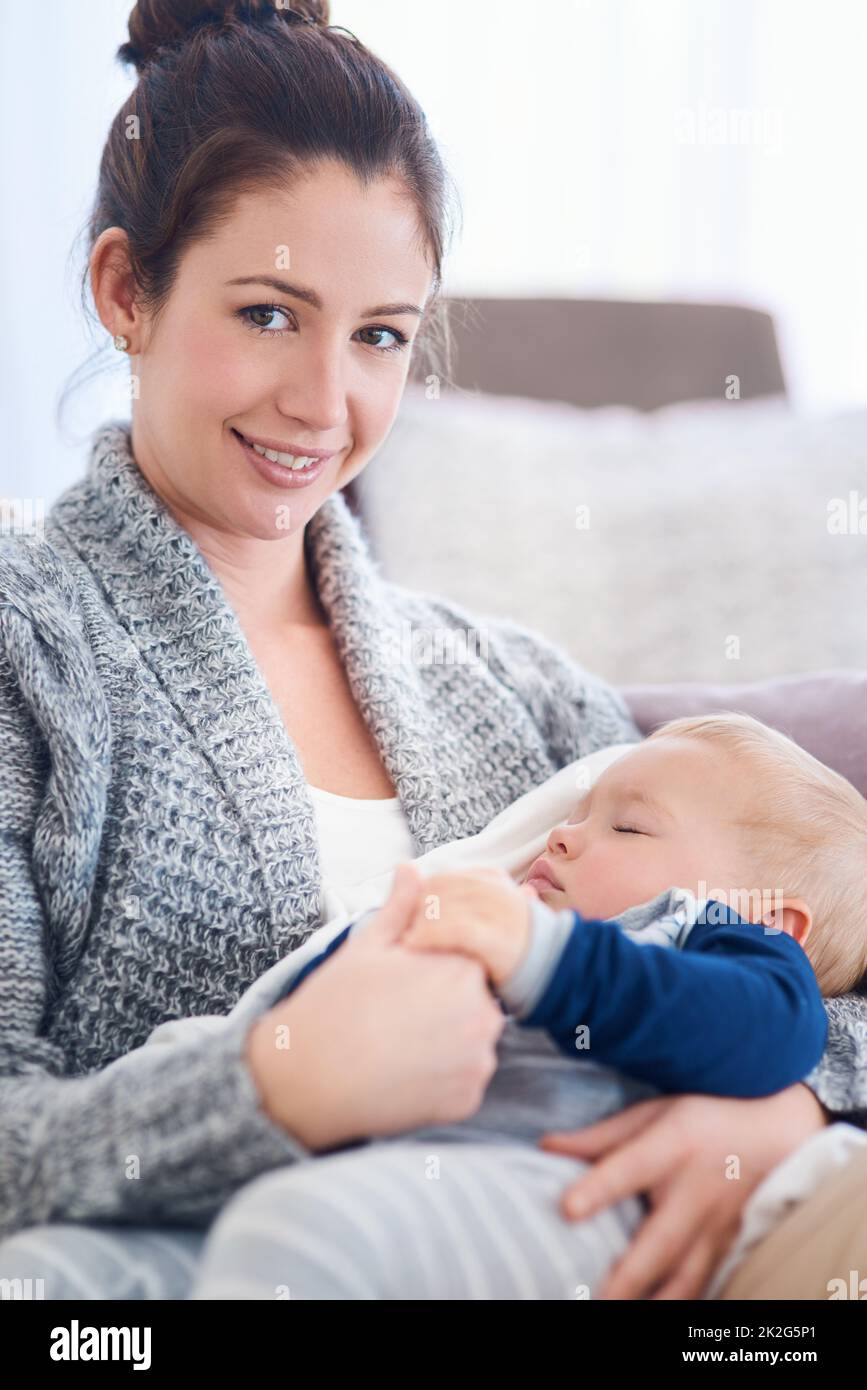 Being a mother is one of lifes greatest treasures. Portrait of a mother holding her sleepy baby boy at home. Stock Photo