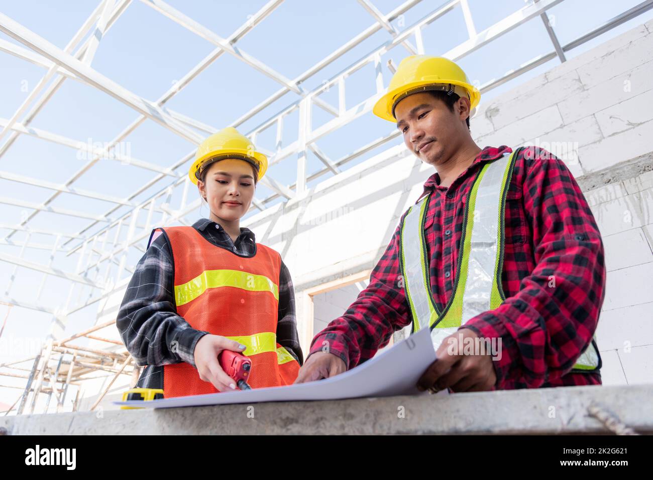 Architect and client discussing help create plan with blueprint of the building at construction site Stock Photo