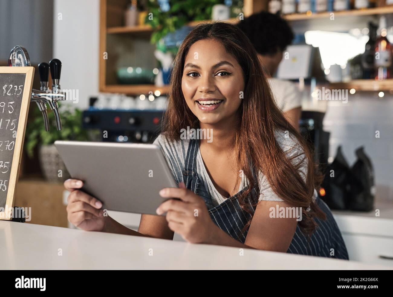Technology is an integral part of how restaurants operate. Portrait of a young woman using a digital tablet while working in a cafe. Stock Photo