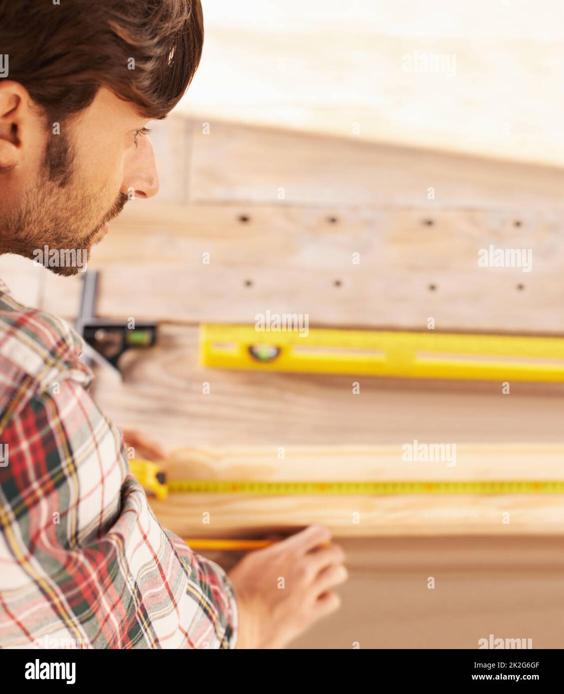 Getting his measurements just perfect. A handyman getting his measurements just perfect with a spirit level and measuring tape. Stock Photo