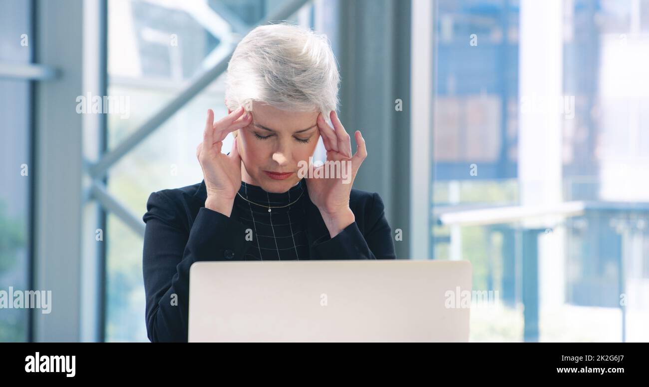 These deadlines are giving me a headache. Shot of a mature businesswoman looking stressed out while working in an office. Stock Photo