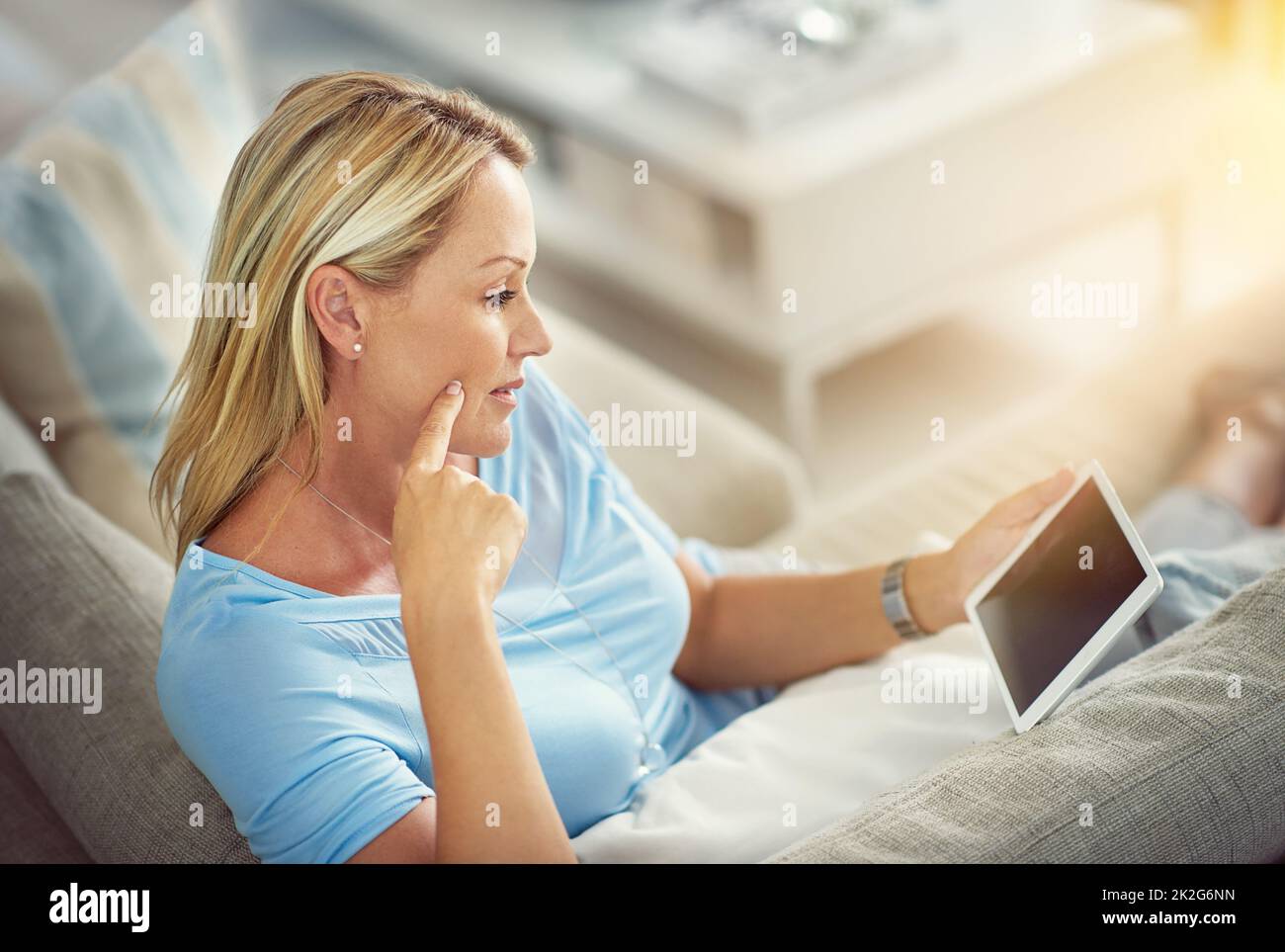 Timeout with her tablet. Shot of a mature woman relaxing on the sofa with a digital tablet. Stock Photo
