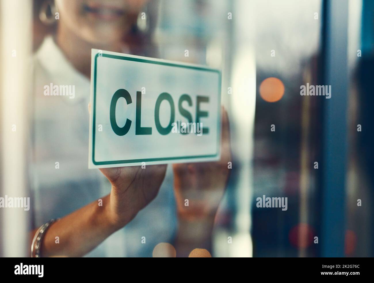 Closing time. Closeup shot of a young business owner hanging up a close sign on the door of her shop. Stock Photo