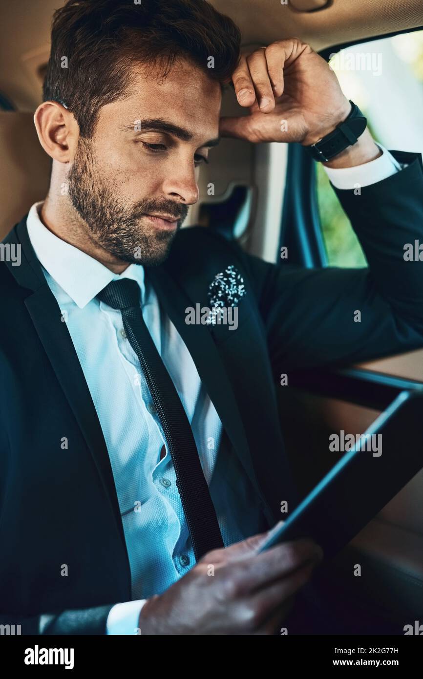 Checking all updates on my way to the office. Cropped shot of a handsome young corporate businessman using a tablet while commuting. Stock Photo