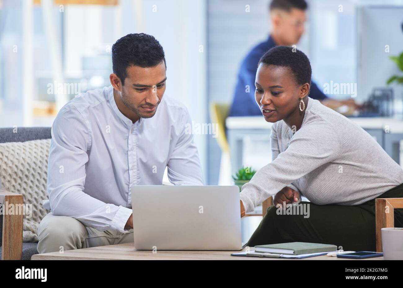 Id go with this one. Shot of two businesspeople discussing something on a laptop while sitting together in an office. Stock Photo