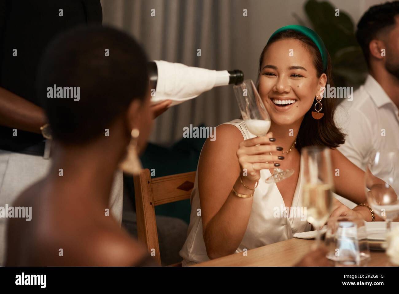 I cant pass up on more champagne. Shot of an unrecognizable man standing and pouring champagne into a glass for a friend during a dinner party. Stock Photo