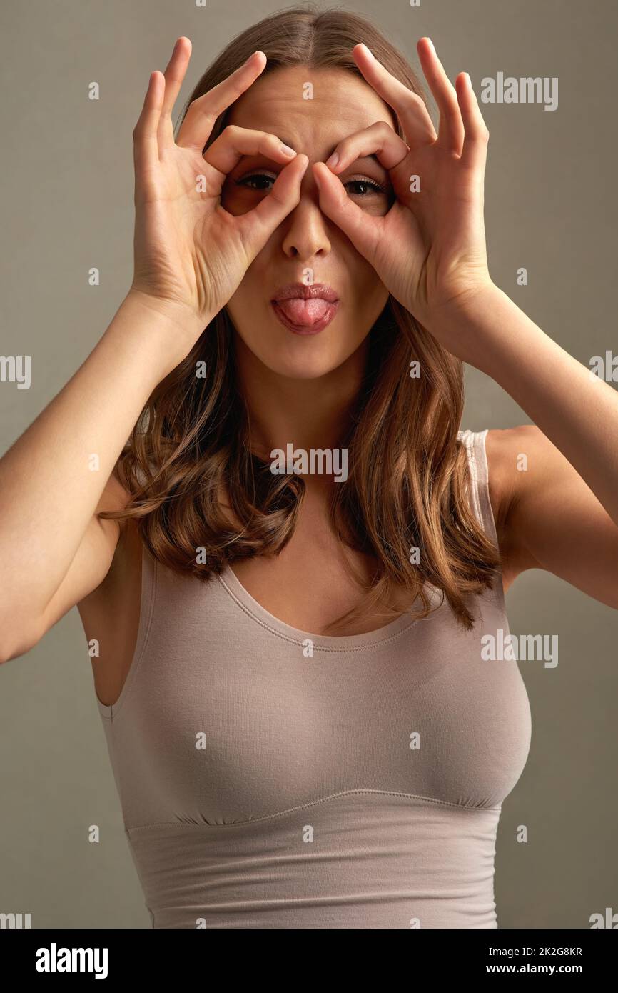 Like what you see. Studio portrait of an attractive young woman making a face against a brown background. Stock Photo