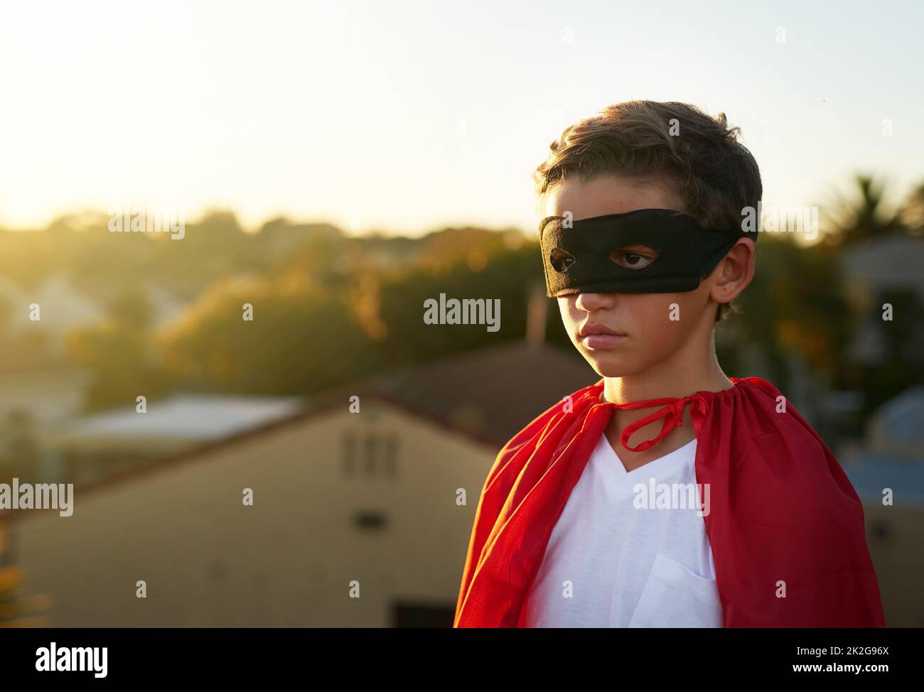The city needs him. Shot of a young boy in a cape and mask playing superhero outside. Stock Photo
