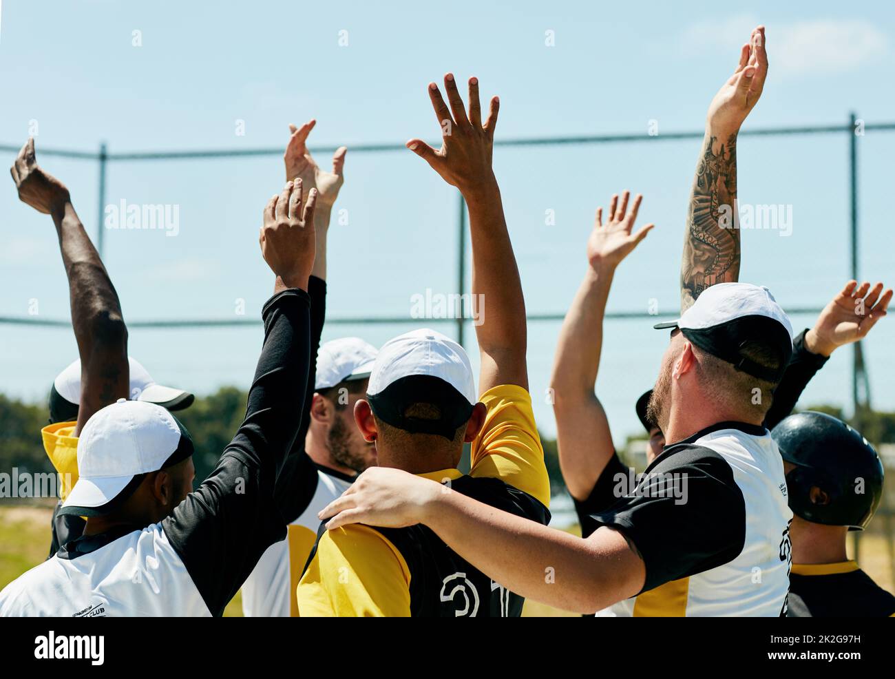 Raise your hand if youre about to give in your best. Cropped shot of a team of young baseball players cheering with their arms raised while standing on the field during the day. Stock Photo