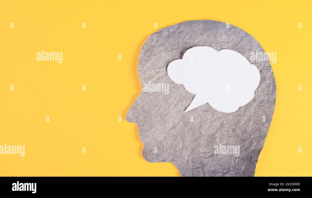 Silhouette of a face, speech bubble in white color, copy space for text, communication, having an opinion, free speech, people talking, yellow background Stock Photo