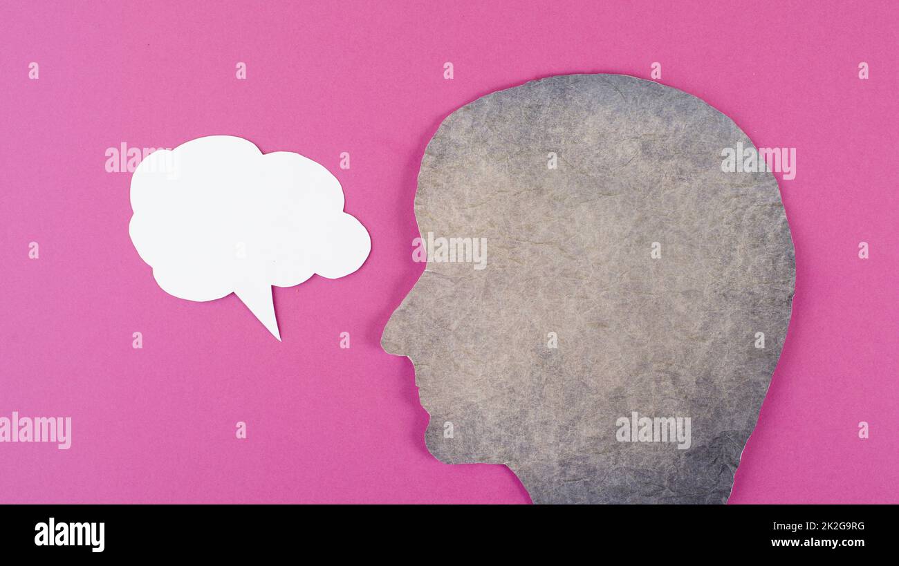 Silhouette of a face, speech bubble in white color, copy space for text, communication, having an opinion, free speech, people talking, pink background Stock Photo