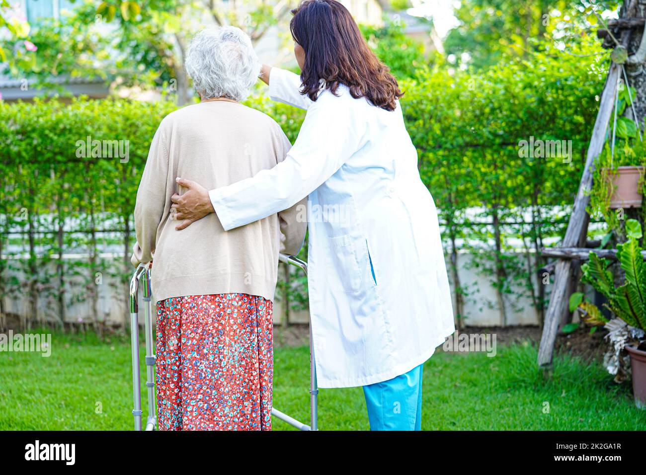 Doctor help Asian elderly woman disability patient walk with walker in