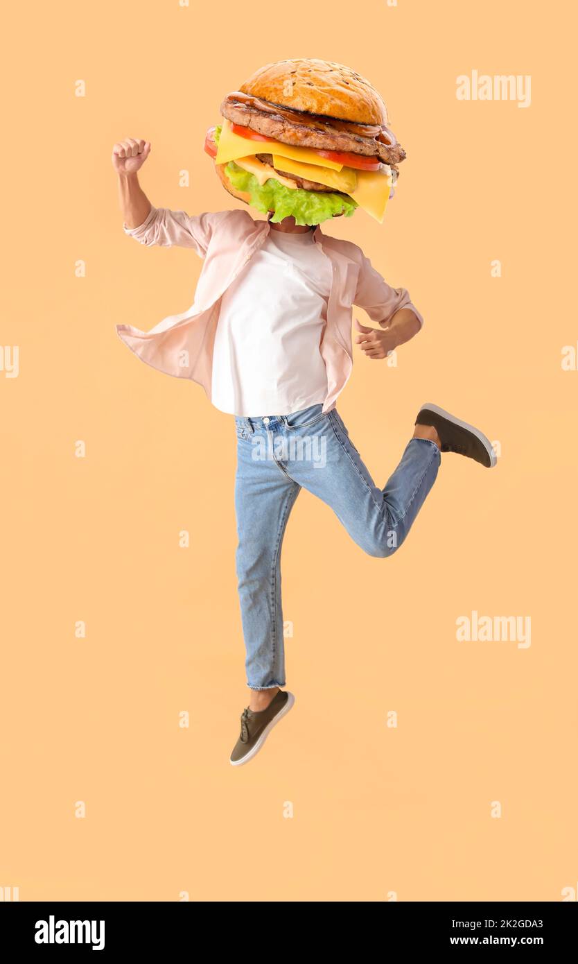 Jumping man with tasty burger instead of his head on beige background ...