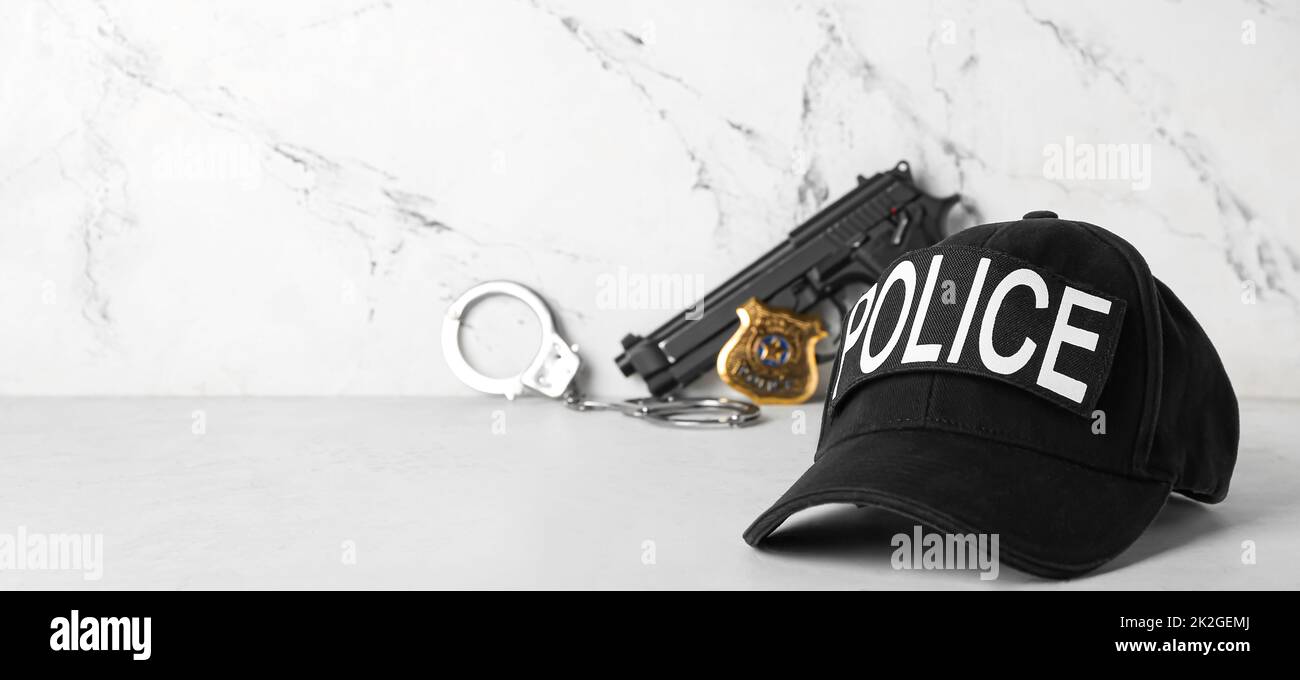 Police Cover Cap of policeman, gun and handcuffs on light background with space for ...