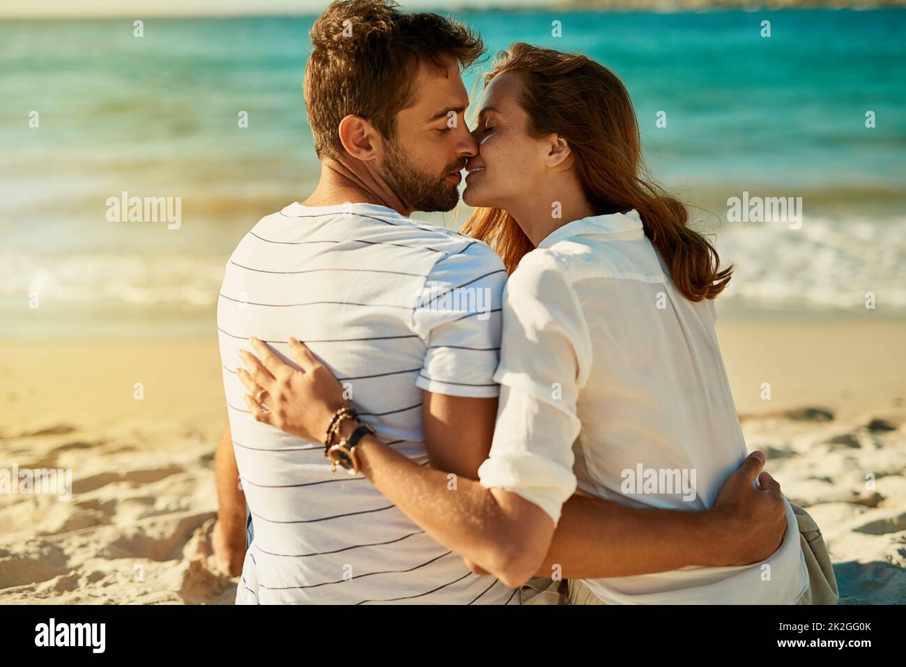Summer romance doesnt get any better than this. Shot of a young couple kissing on a summers day at the beach. Stock Photo