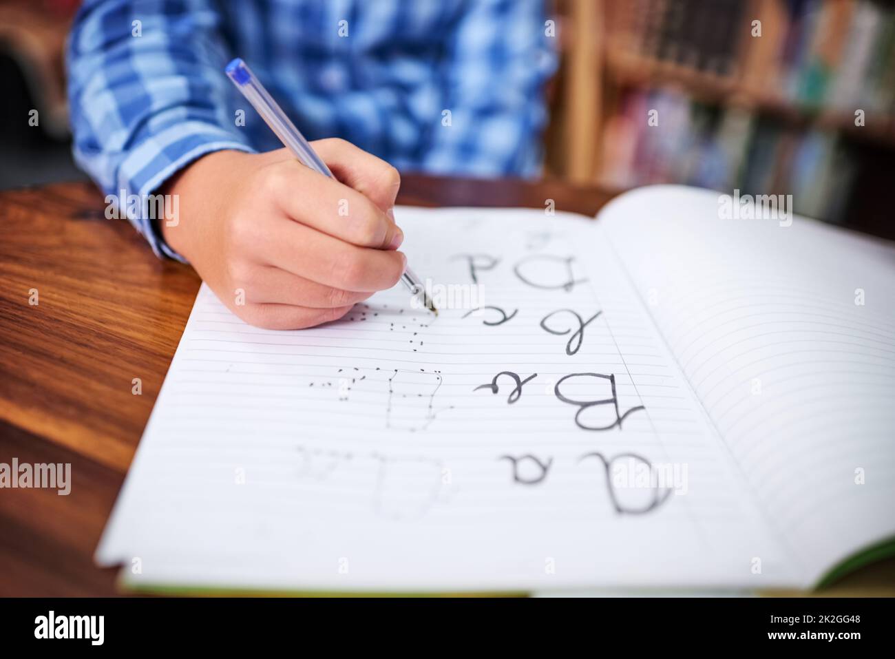 Practising his handwriting. Shot of an unrecognisable young boy writing in a book at school. Stock Photo