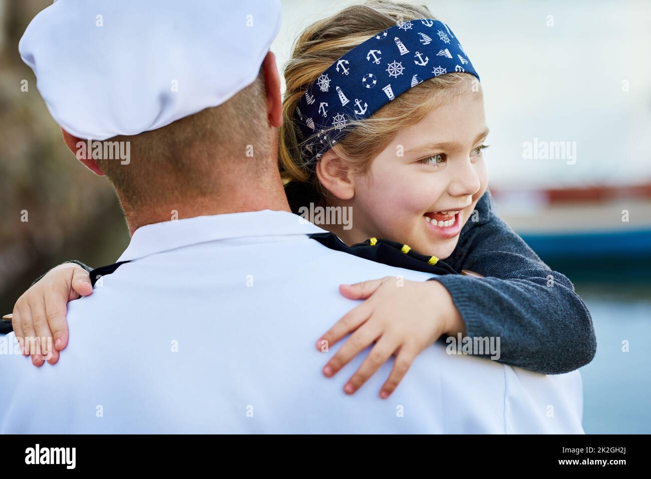 Excited to have her daddy back home. Rearview shot of a father in a navy uniform hugging his happy little girl. Stock Photo