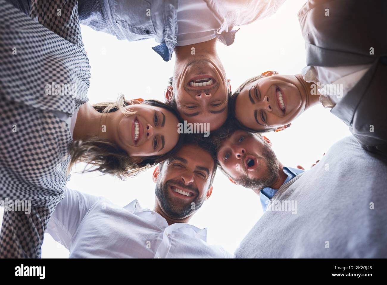 We make one dynamic team. Low angle shot of a group of businesspeople huddled together on their office balcony. Stock Photo