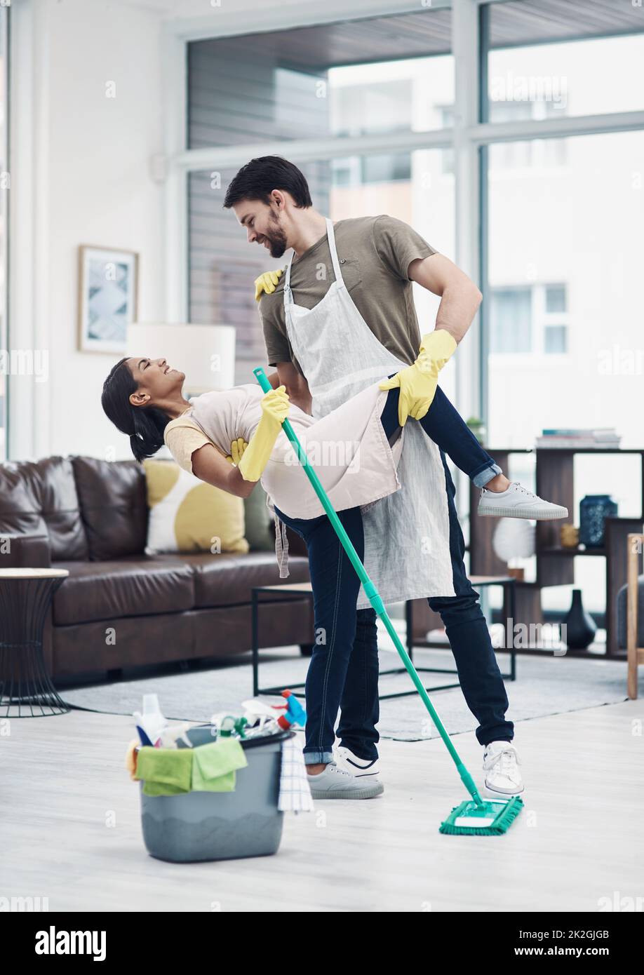 Romance changes everything. Shot of a happy young couple dancing while mopping the floor at home. Stock Photo
