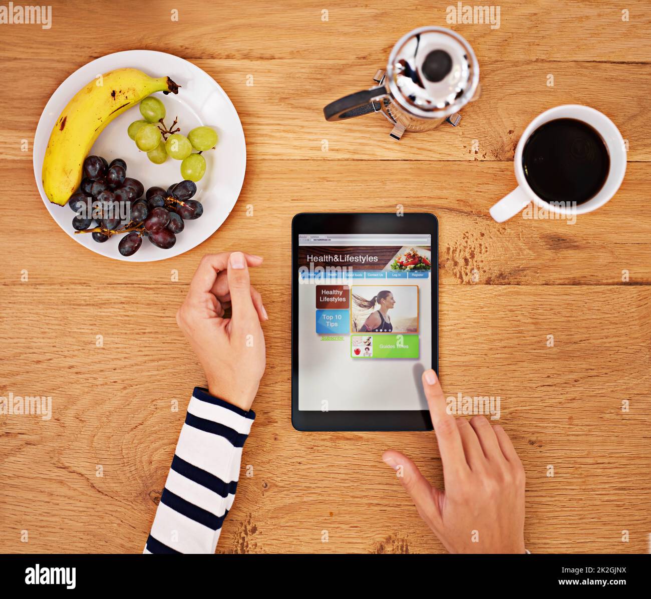 The way to start your day. Shot of an unrecognisable person using a digital tablet at a table. Stock Photo