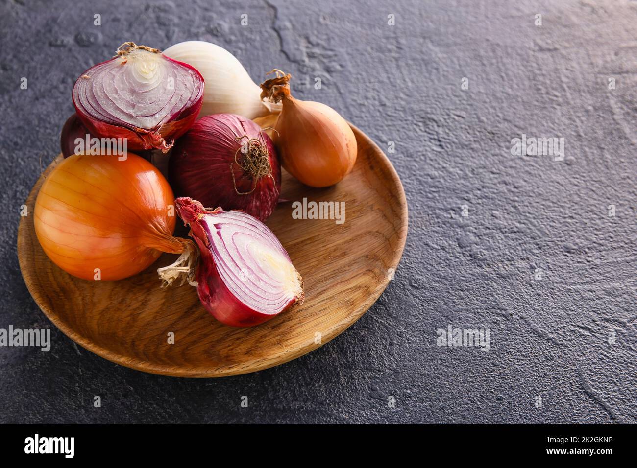 Wooden plate with fresh onion on dark background Stock Photo - Alamy