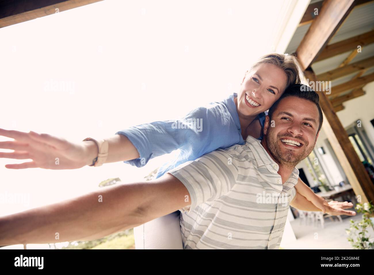 Being kids again in the backyard. Cropped shot of a young handsome man giving his beautiful wife a piggyback ride outside. Stock Photo