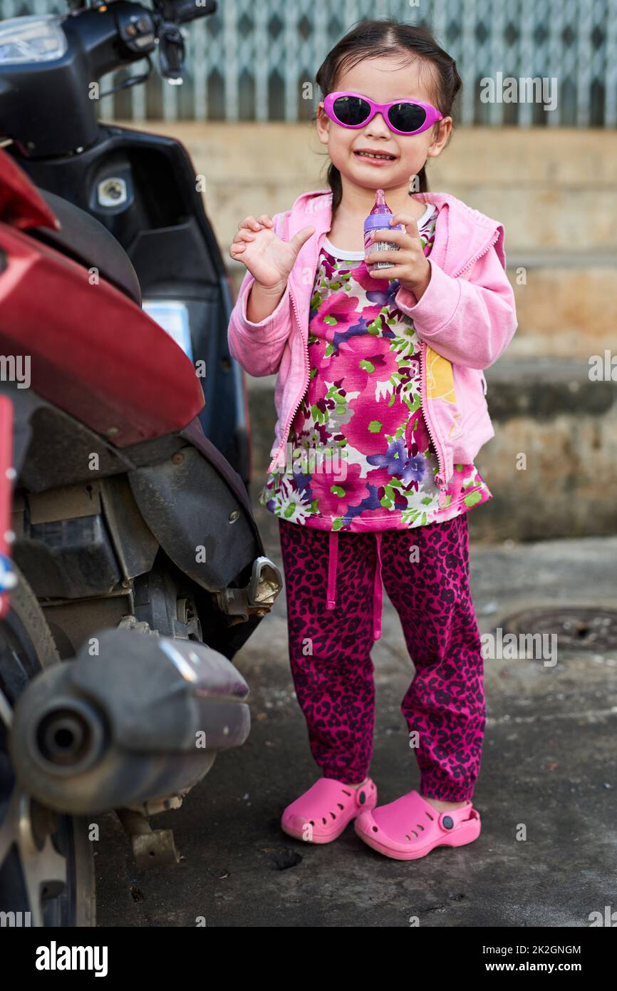 Shes a cool kid. Portrait of an adorable little girl standing alongside a scooter outside. Stock Photo