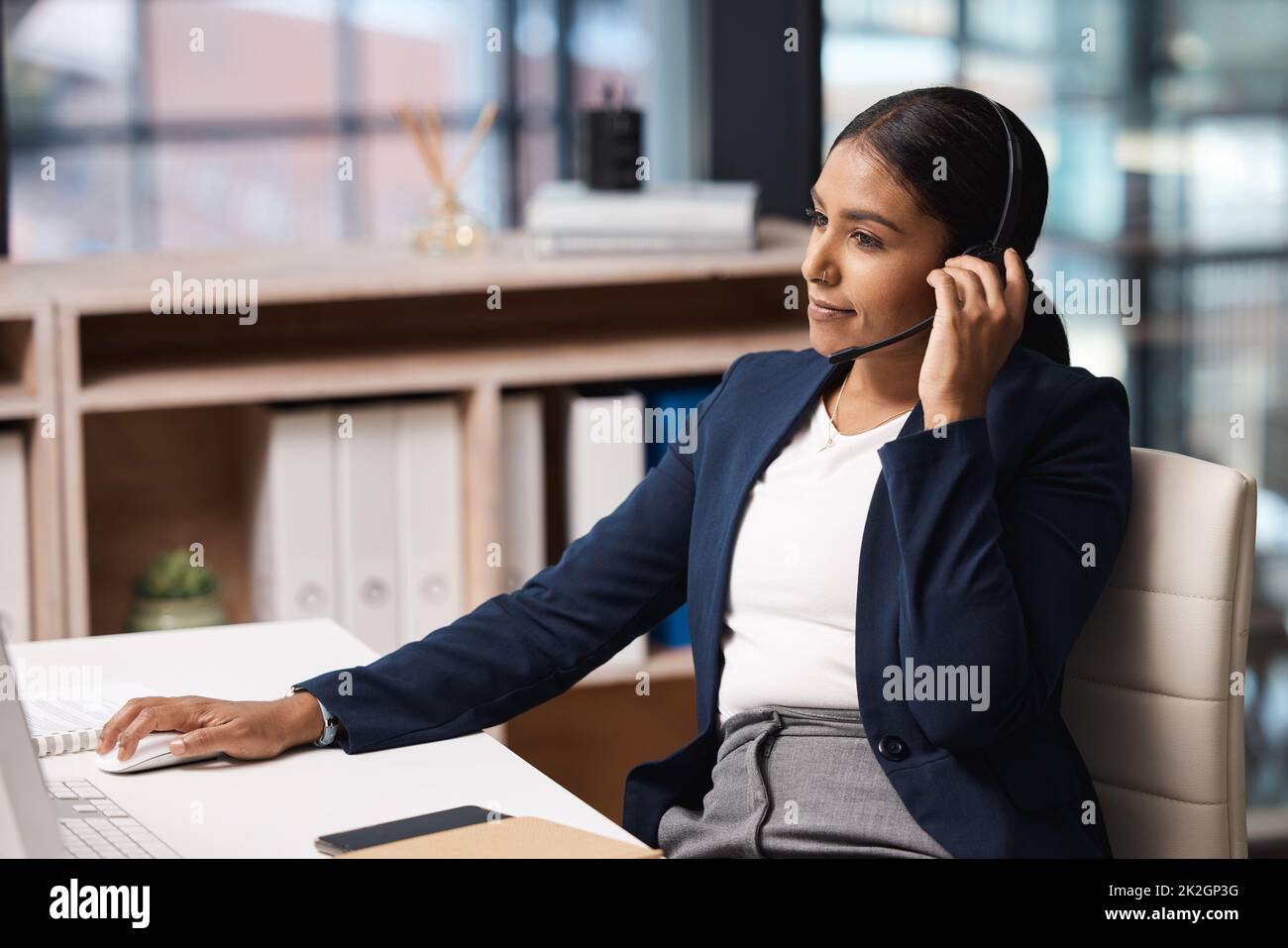 Taking on her role as an efficient agent. Shot of a young businesswoman working on a computer in a call centre. Stock Photo
