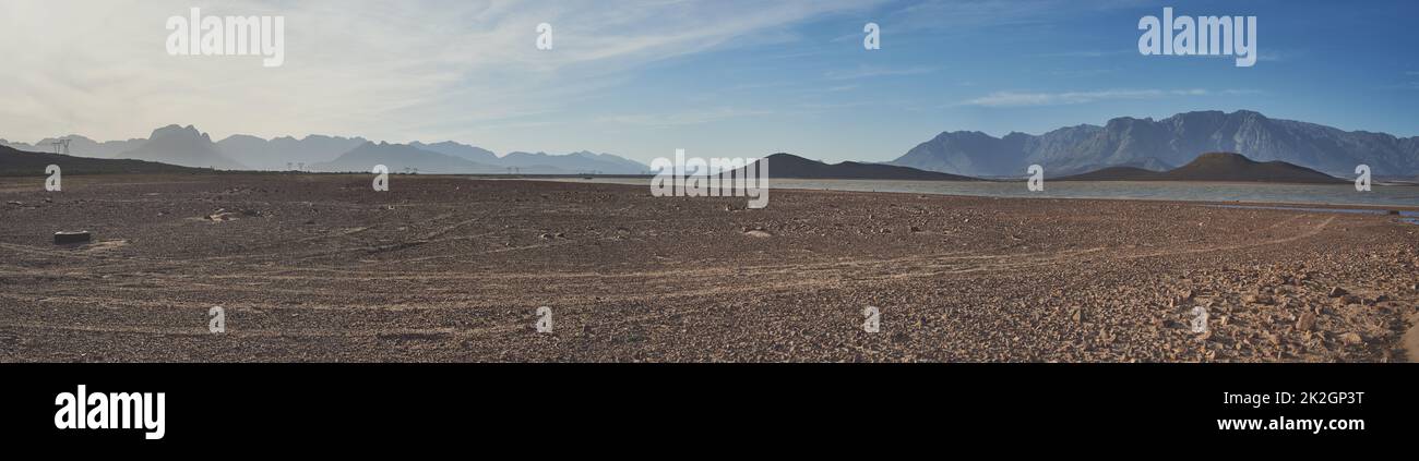 What will you do to save water. Shot of a desolate landscape during the day with a small dried out dam in the middle with the words water crisis displayed in the middle of the image. Stock Photo