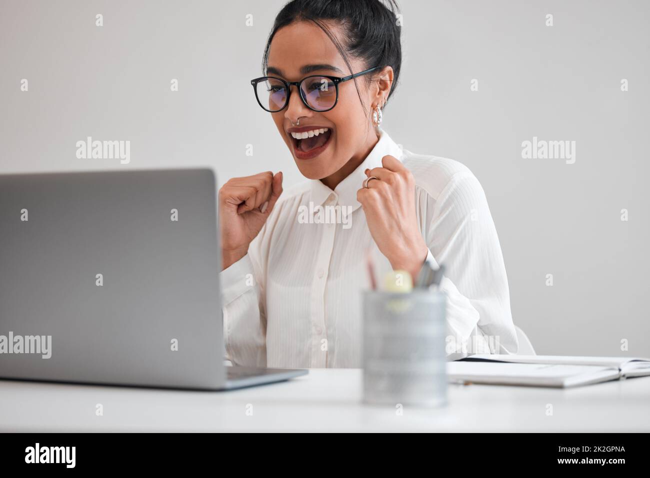 Yes Another client on boarded. Cropped shot of an attractive young businesswoman cheering while working on her laptop at a desk in the office. Stock Photo