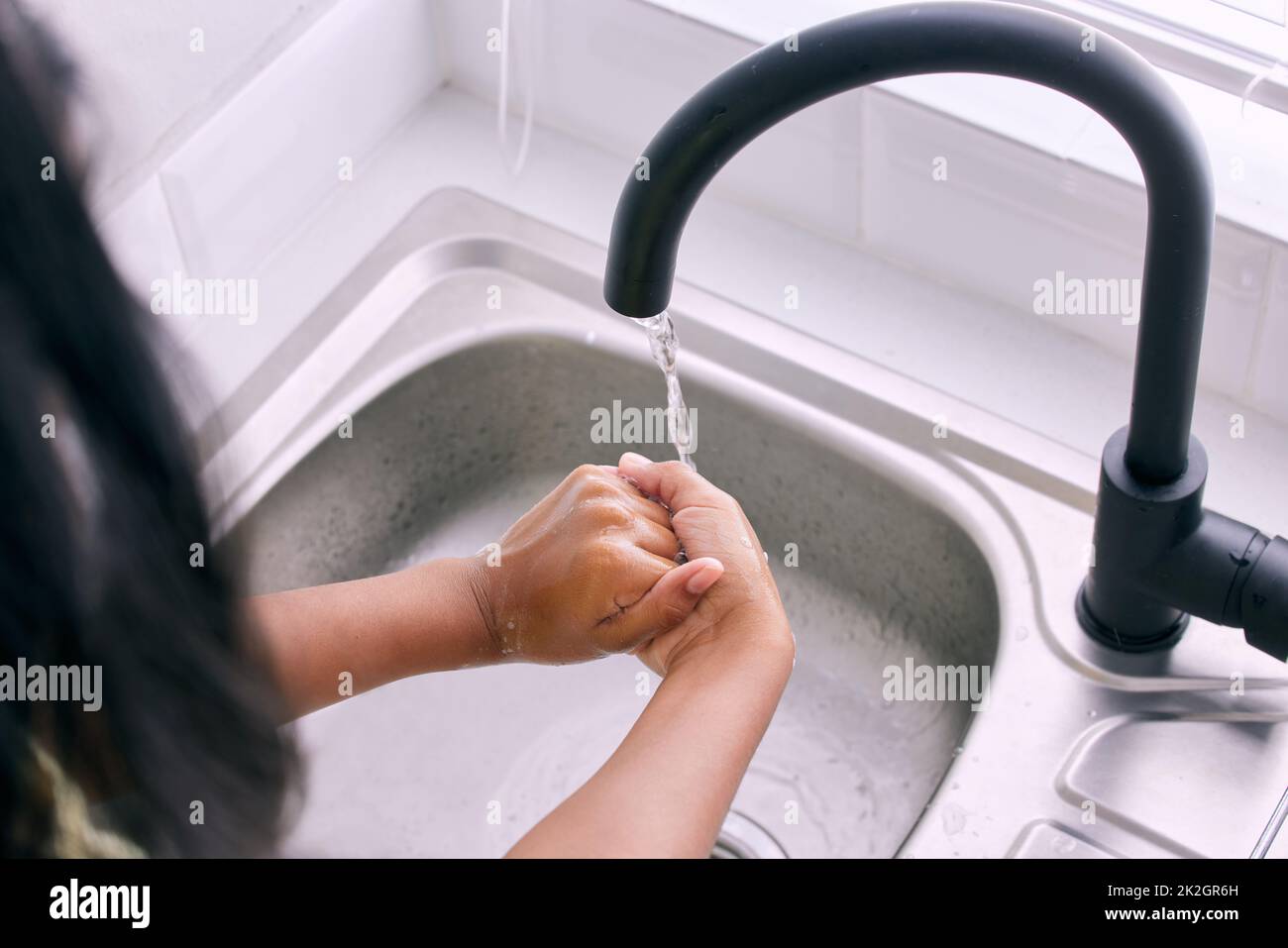 Clean hands= A healthier you. Cropped shot of an unrecognizable girl washing her hands by the kitchen sink. Stock Photo